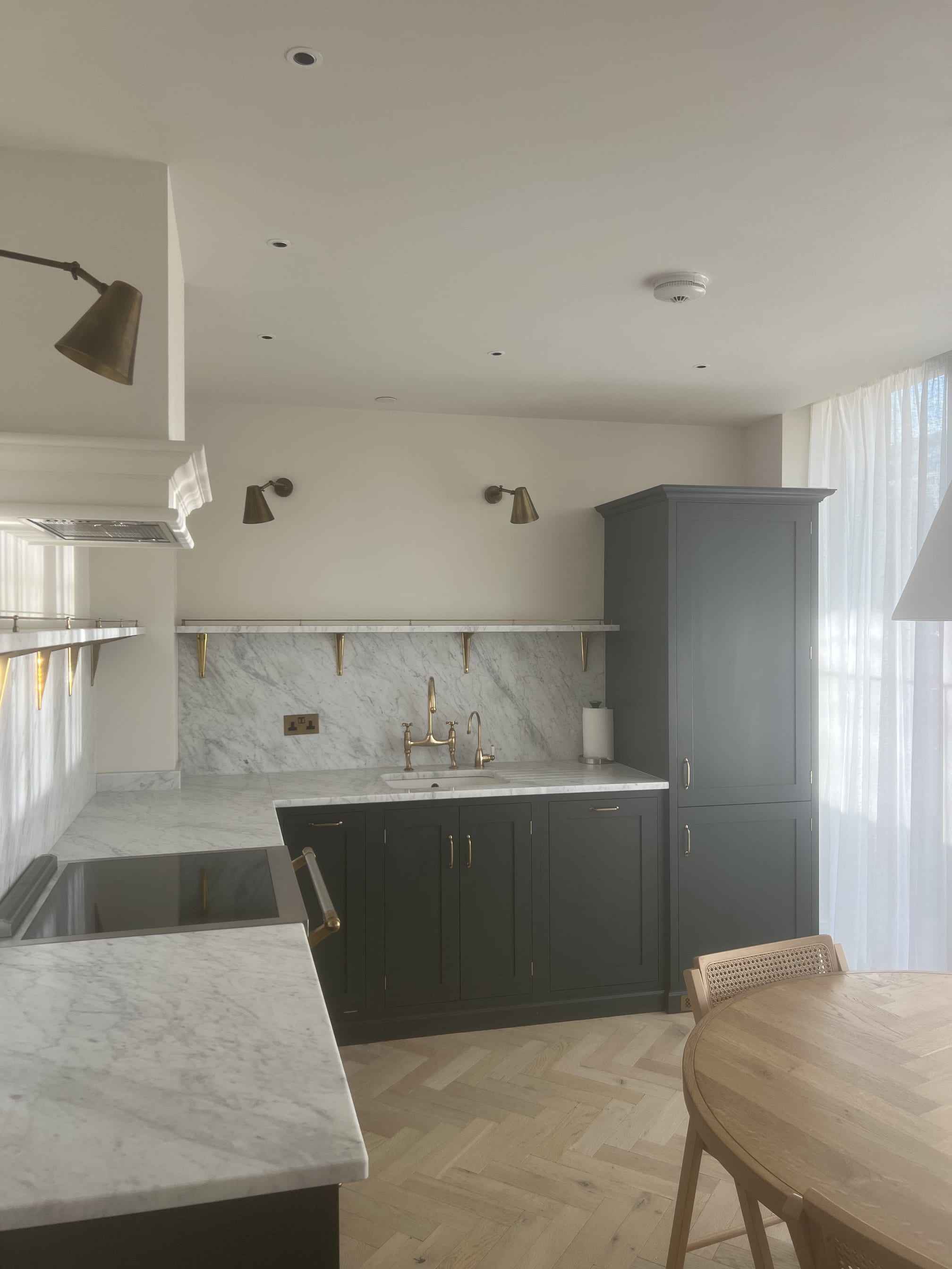 Kitchen with marble worktops and splashback, brass taps and dark grey cabinets