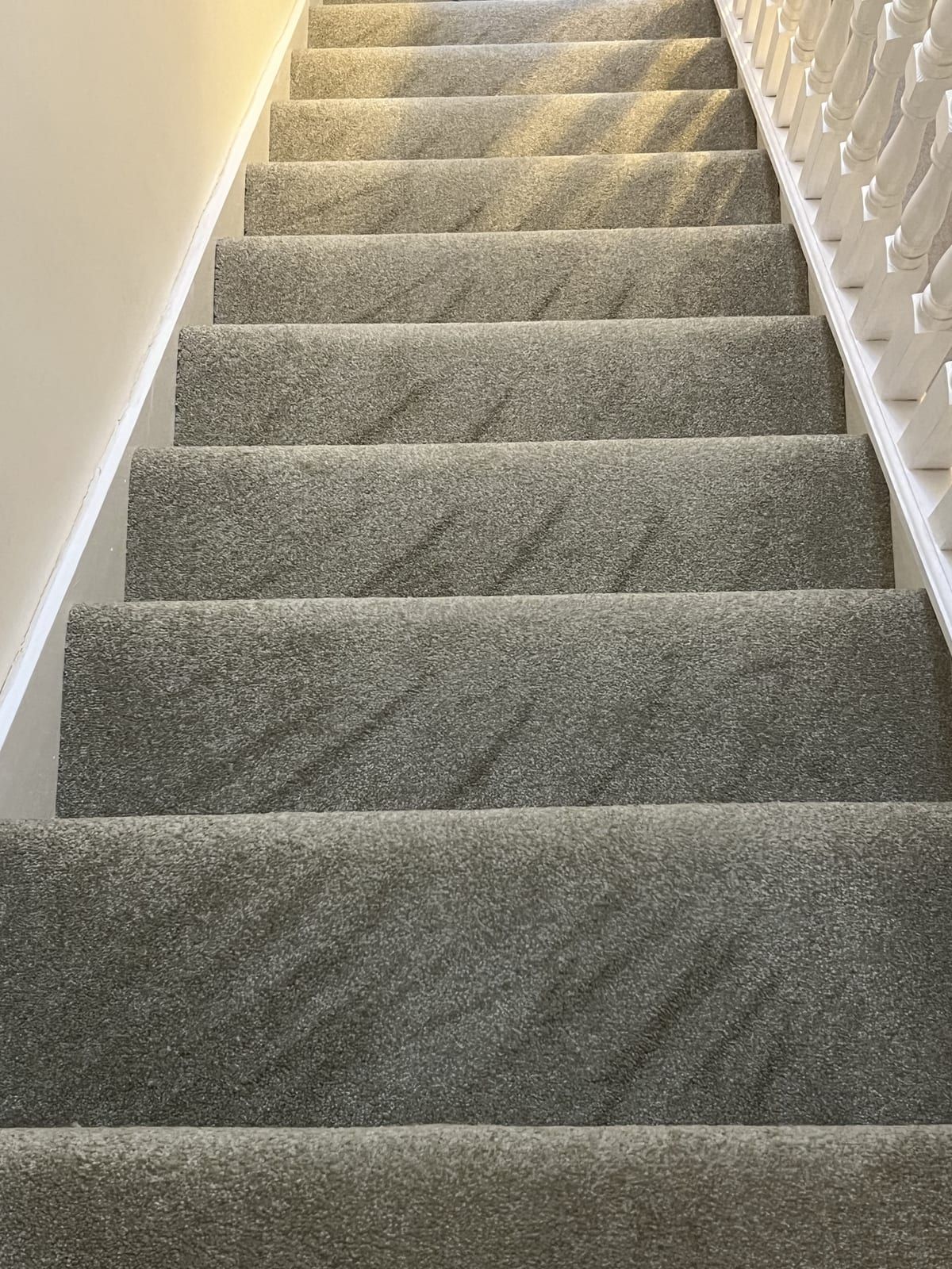 Grey carpeted staircase with white banisters